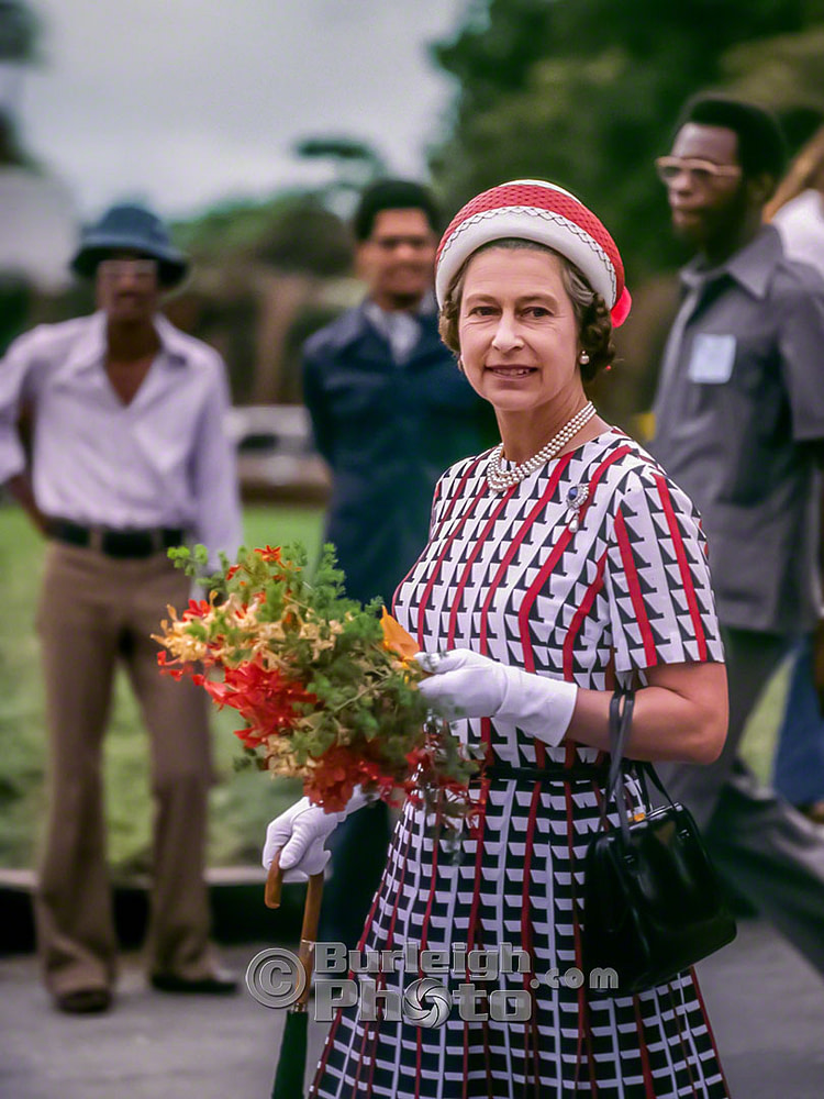 Queen Elizabeth holds a bouquet of Pride of Barbados flowers as she begins her first walkabout of the trip